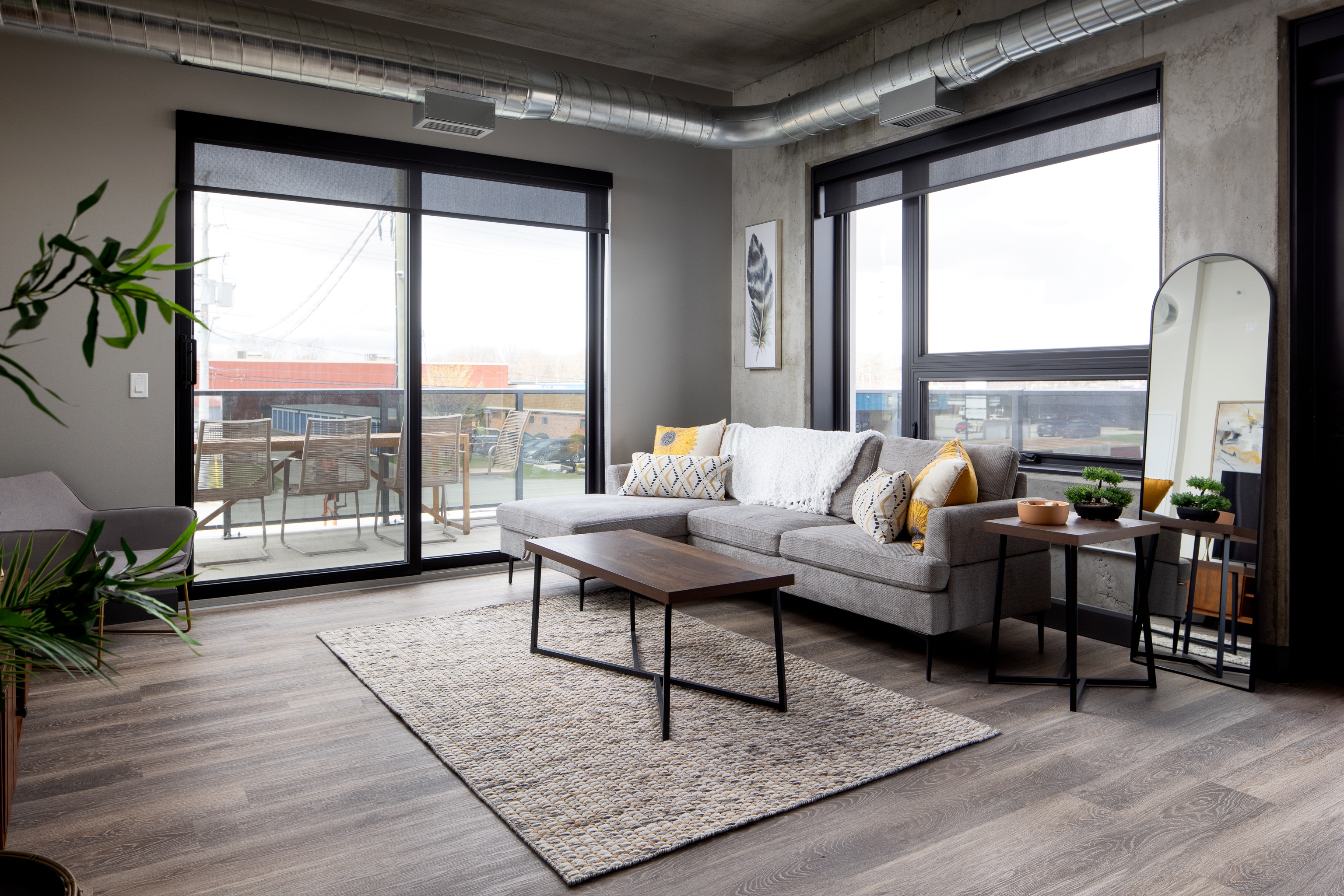 A living room with a grey sofa and a coffee table in front of a large window.